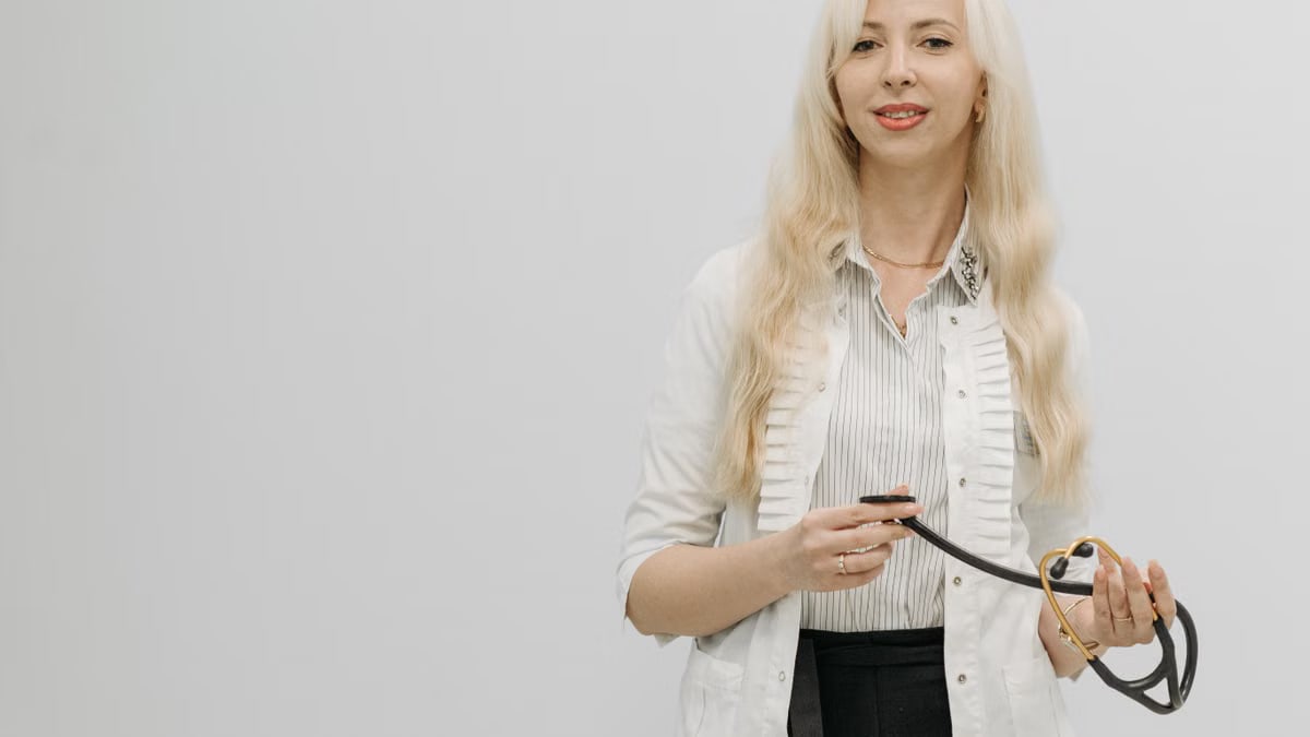 Blonde female doctor with a stethoscope against a white background, representing healthcare professionals.
